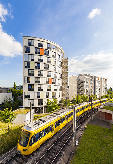 A yellow tram passing by high-rise residential buildings